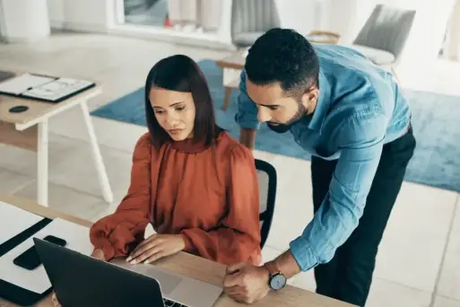 Two office workers looking at a computer